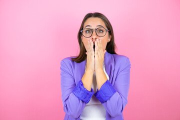 Young beautiful business woman over isolated pink background with her hands over her mouth and surprised