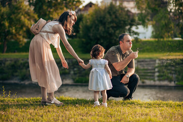 Naklejka na ściany i meble Happy family, mother, father and little daughter have fun outdoors