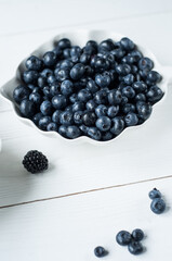 Panoramic shot of scattered blackberries, blueberries and chia seeds on white wooden table isolated on black