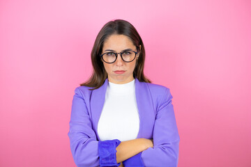 Young beautiful business woman over isolated pink background skeptic and nervous, disapproving expression on face with crossed arms