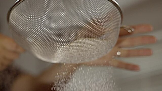 Woman sieving Flour in kitchen