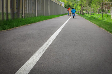 children on bicycles on the road, solid white line, road safety, traffic rules, bike path in the park