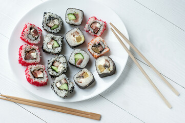 Traditional japanese sushi pieces placed between chopsticks, separated on light blue pastel background. Very high resolution image.