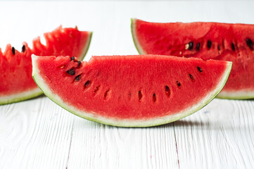 Fresh sliced watermelon and watermelon pieces on a wooden background.