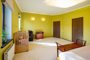 Spacious bedroom in private house. Modern luxury interior. Wooden dresser. Leather chair. Baby bed.