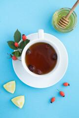 Top view of tea with dogrose and honey on the blue surface
