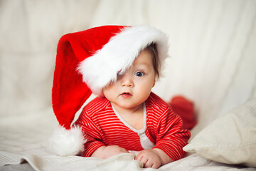 Smiling happy baby in christmas santa's hat and red overalls - 376748218