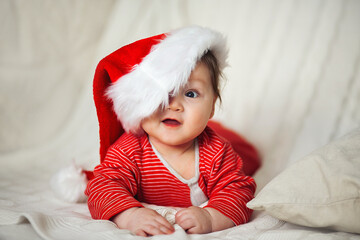 Smiling happy baby in christmas santa's hat and red overalls - 376748260