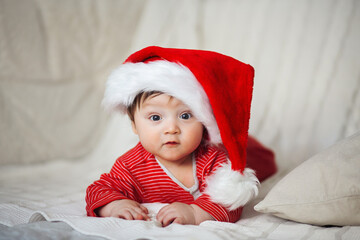 Smiling happy baby in christmas santa's hat and red overalls - 376748284
