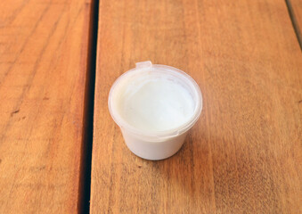 Fototapeta na wymiar White cream in a plastic jar on a wooden background.