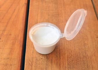 White cream in a plastic jar on a wooden background.