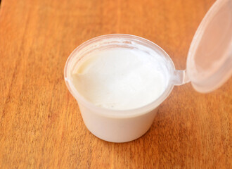 White cream in a plastic jar on a wooden background.