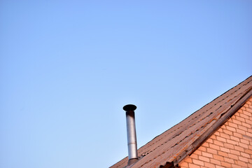 Fototapeta na wymiar The house with an iron chimney pipe furnace