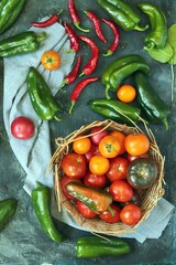 
Tomatoes, red and green peppers on the table, in a basket, top view, flatley, harvest concept, healthy seasonal food, home cooking