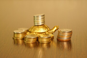 Metal turtle with coins on a uniform background. Symbol of financial stability.