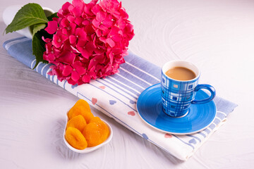 blue cup of coffee, dried apricots, branch of pink hydrangea