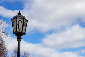 Fototapeta na wymiar Vintage street lamp with patterns on a blue sky background with clouds