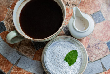 Obraz na płótnie Canvas Vegetarian coconut milk pudding, Chia seeds with mint leaf, coffee mug and cream in a milk jug