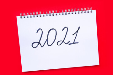 New Year and Christmas concept. The inscription 2021 in a notebook with a spiral on a red background.