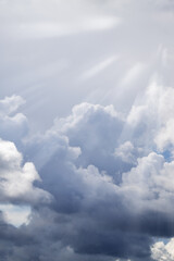 Bright sunlight shines through the rain clouds. Autumn - spring weather. Dramatic clouds. Vertical photo