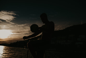 Fototapeta na wymiar Silhouette of man playing football on the beach