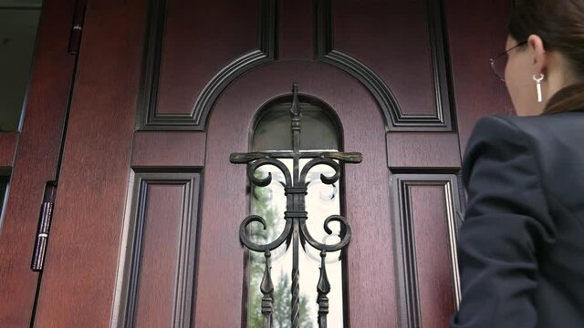 The woman and the state structure are persistently knocking on the door of a private house. Civil servant with a summons