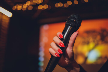 Microphone and female singer close up. Woman singing into a microphone, holding mic with hands.