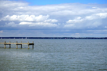 Steg, Bootssteg ragt ins Wasser, Segelboote in der Ferne