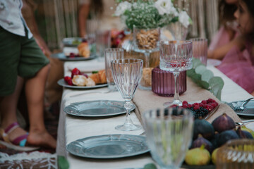 Beautiful dishes on the table with fruits in the background. Close-up of modern table setting in the yard. Boho-chic style concept