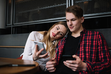 Focused young couple with smartphones in cafe