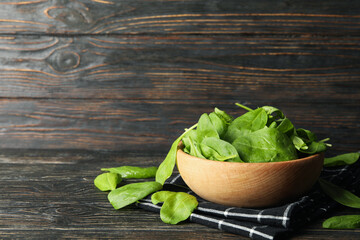 Wooden bowl with spinach and napkin on wooden background