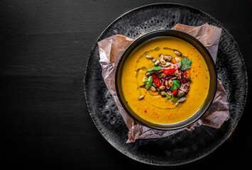Pumpkin soup in black plate on black wooden table background