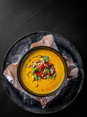 Pumpkin soup in black plate on black wooden table background