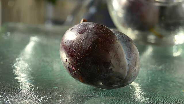 Blue Plums bouncing and rolling on glass surface