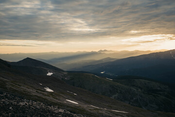 Mountainside at dawn. Gold sunlight coming through.