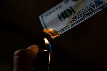 Burning dollar and lighter in hand closeup