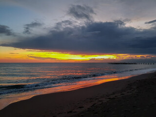 Sunset on the sea: red-orange sky with dark clouds and a piece of beach