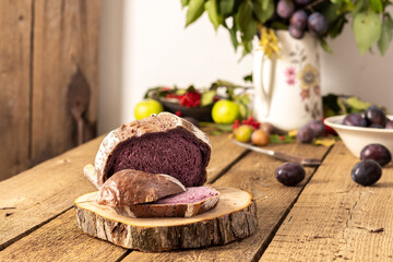 Blueberry and plum bread on a wooden background, berries and fruits on the table, plum branches in a vase, rustic interior