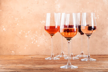 Rose wine glasses assortment on wine tasting. Degustation different varieties, colors and shades of pink wine concept. Beige background