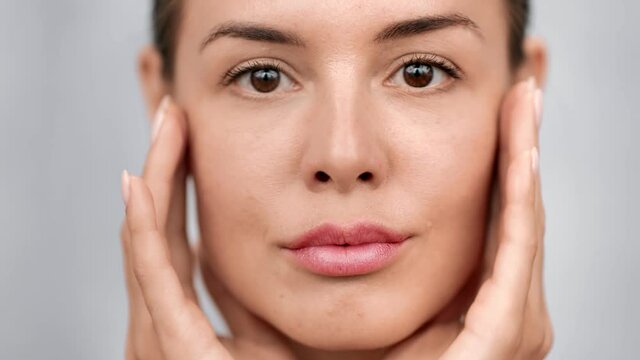 Smiling woman applying moisturizer cream enjoying facial care. Close up shot on 4k RED camera