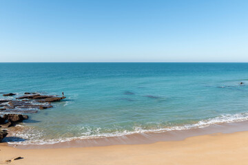Paisaje rocoso y un hombre pescando en las rocas, en la playa de Cabo de Roche o Calas de Roche, ubicada en Conil de la Frontera, en la provincia de Cádiz, España.
