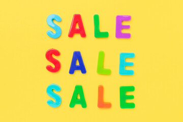 Multicolored text Sale on yellow background. Creative flat lay composition