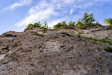 Rock with soil layers against blue sky.