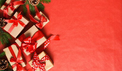 Beautiful Christmas composition on a red background with fir. Gift boxes with red ribbons.