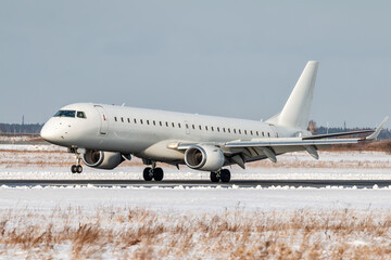 Fototapeta na wymiar Landing of a white passenger jet plane on the runway of a winter airport