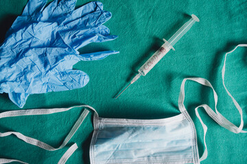 Surgical Facial Mask, Medical Syringe, And Blue Latex Gloves On A Green Background