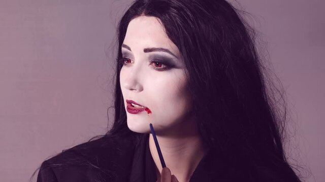 Young woman doing halloween makeup with blod effect