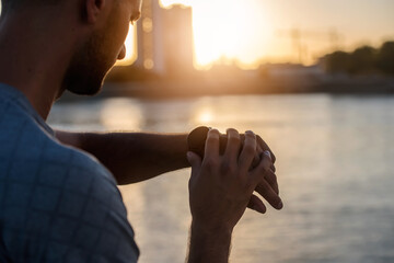Young handsome sporty jogger taking break from exercising outdoors looking on a smart fitness watch