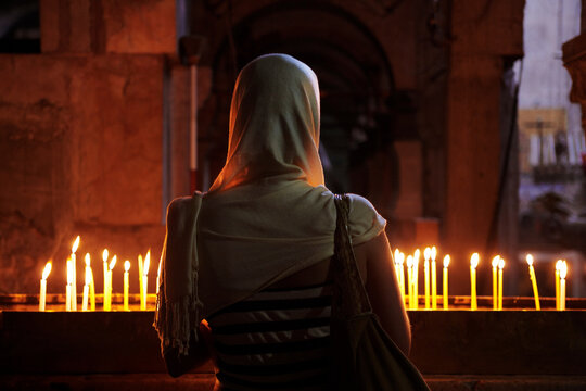Woman in front of candles at Church of the Holy Sepulchre, Jerusalem, Israel