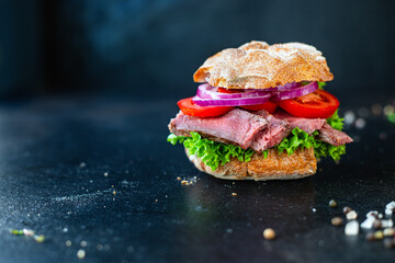 sandwich with meat and vegetables loaf of bread, tomato, lettuce, medium or rare steak on the table serving portion size top view place copy space for text